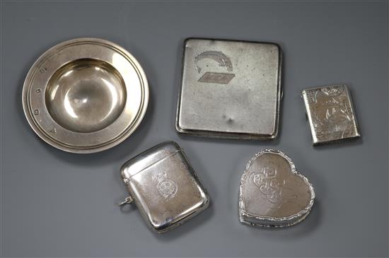 Two silver vestas, a silver heart shaped pill box, a silver cigarette case and a small silver Armada dish.